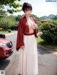 A woman in a red kimono standing next to a red car.