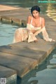 A woman in a white lingerie sitting on the edge of a pool.