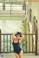 A woman in a black bathing suit and hat posing for a picture.