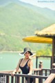 A woman in a black bathing suit and a white hat.