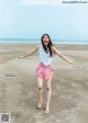 A woman standing on a beach with her arms outstretched.