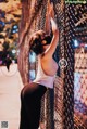 A woman leaning against a chain link fence.