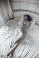 A naked woman laying on a bed with white sheets.