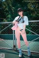 A woman standing on a tennis court holding a pink hat.