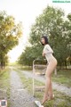 A woman in a white bodysuit standing next to a shopping cart.