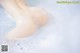 A close up of a person's feet in a bathtub filled with foam.