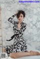 A woman in a black and white dress sitting on a white table.