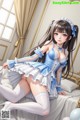 A woman in a blue and white dress sitting on a bed.