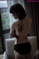 A woman with a tattoo on her back sitting on a chair.