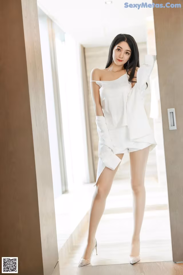 A woman in a white dress posing for a picture.