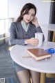 A woman sitting at a table with a cup of coffee.