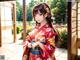 A woman in a red kimono standing in front of a door.