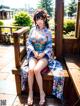 A woman in a kimono sitting on a wooden bench.