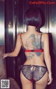 A woman with a tattoo on her back is standing in an elevator.