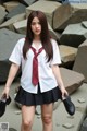 A woman in a school uniform is holding a pair of shoes.