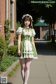 A woman in a green and white dress is walking down a sidewalk.