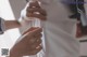 A woman is sewing a white shirt on a mannequin.