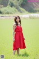 A woman in a red dress standing in a green field.