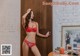 A woman in a red bra and panties standing in front of a door.