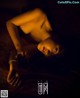 A naked woman laying on a bed in the dark.