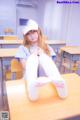 A girl sitting on a desk in a classroom.