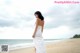 A woman in a white dress standing on a beach.