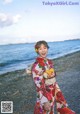 A woman in a colorful kimono standing on a beach.