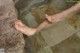 A woman's bare feet in a bathtub of water.